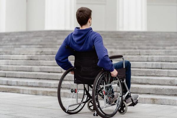 Person im Rollstuhl vor Stufen