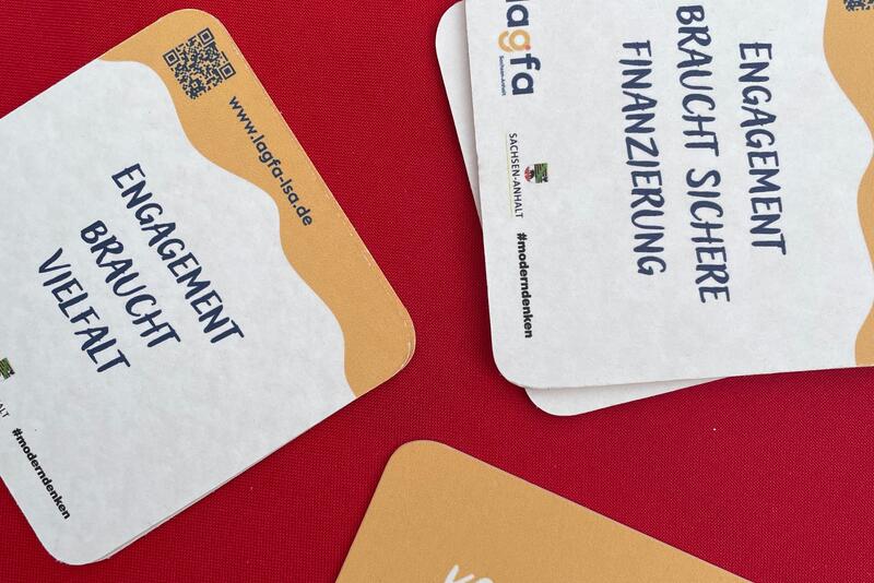 Auf einem Tischen liegen Bierdeckel mit Forderungen um Ehrenamt zu fördern. 