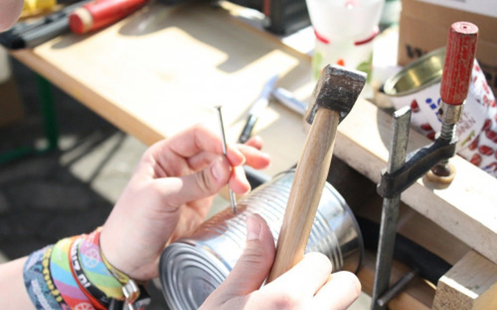 Hände hämmern einen Nagel in eine Blechdose